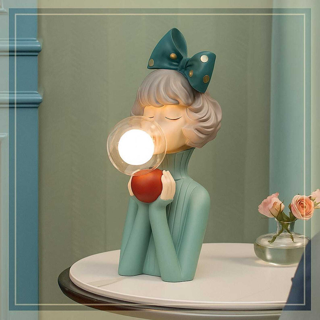 Decorative lamp shaped like a girl with a bow, holding a light bulb, on a table.