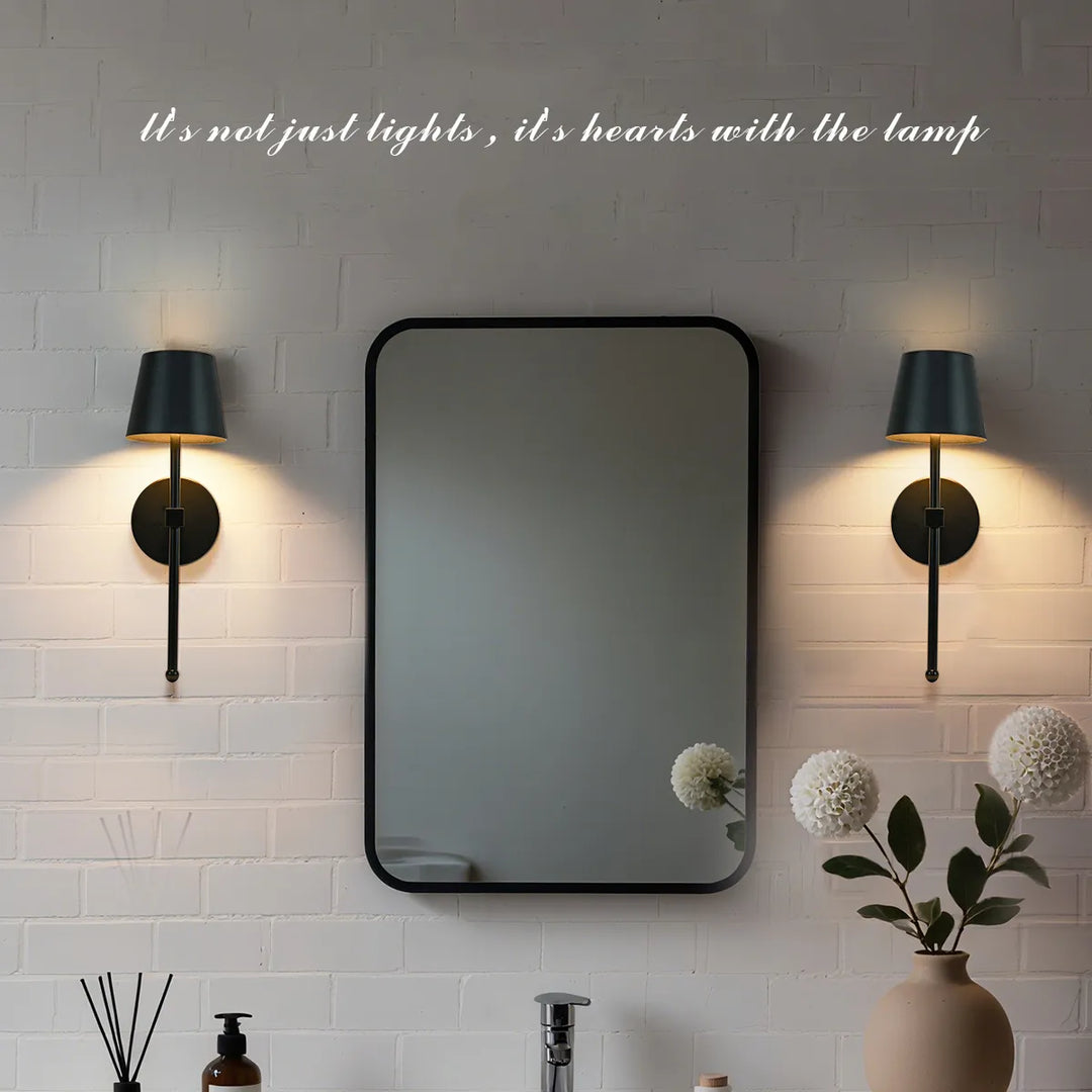 Bathroom setting with a mirror flanked by two wall lights on a tiled wall.