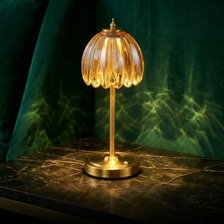 Table cordless lamp with green glass shade displayed on a marble table.
